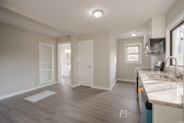 kitchen with white cabinetry, stainless steel appliances, wood-type flooring, and light stone counters