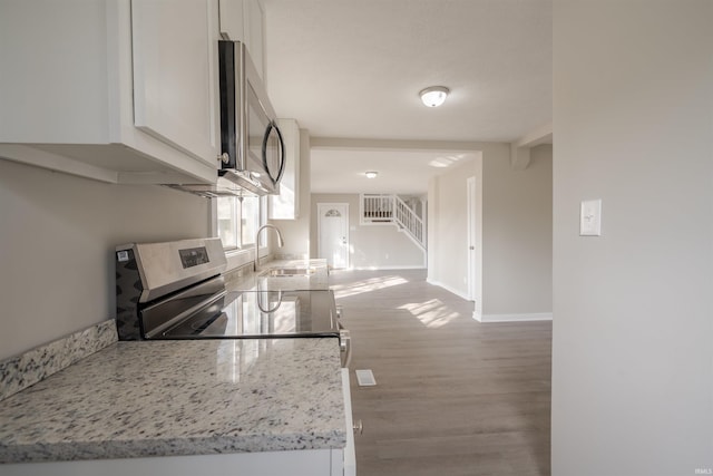 kitchen with white cabinetry, sink, hardwood / wood-style flooring, and light stone countertops