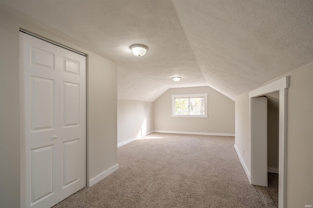 additional living space with carpet, a textured ceiling, and vaulted ceiling