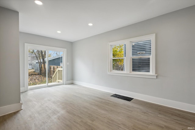 spare room featuring wood-type flooring and a healthy amount of sunlight