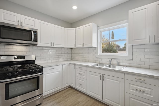 kitchen with stainless steel appliances, white cabinets, and backsplash