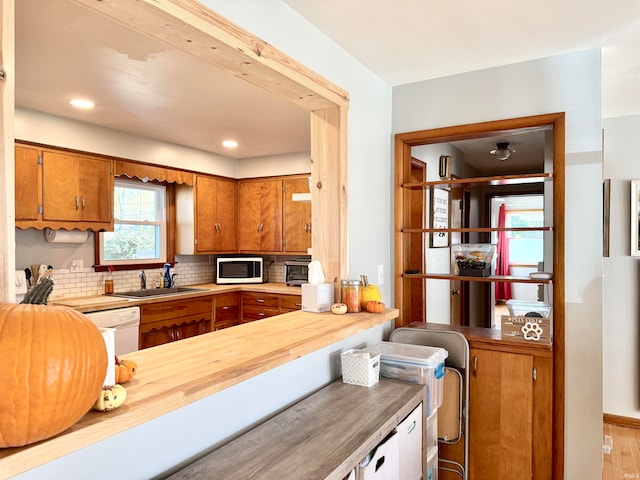 kitchen featuring butcher block counters, decorative backsplash, sink, white appliances, and light hardwood / wood-style flooring