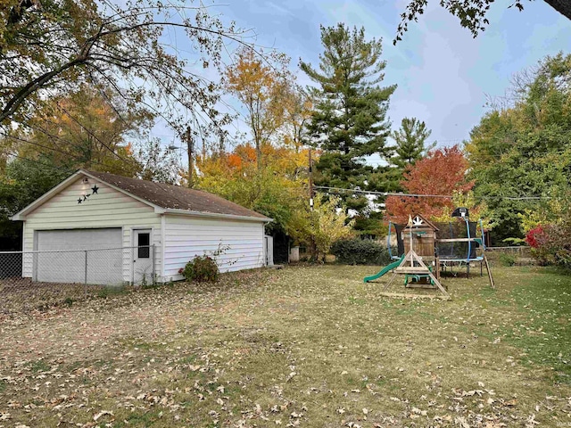 view of yard featuring a garage, a playground, and an outdoor structure