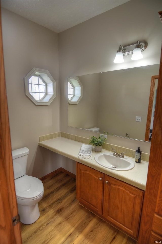 bathroom featuring wood-type flooring, toilet, and vanity