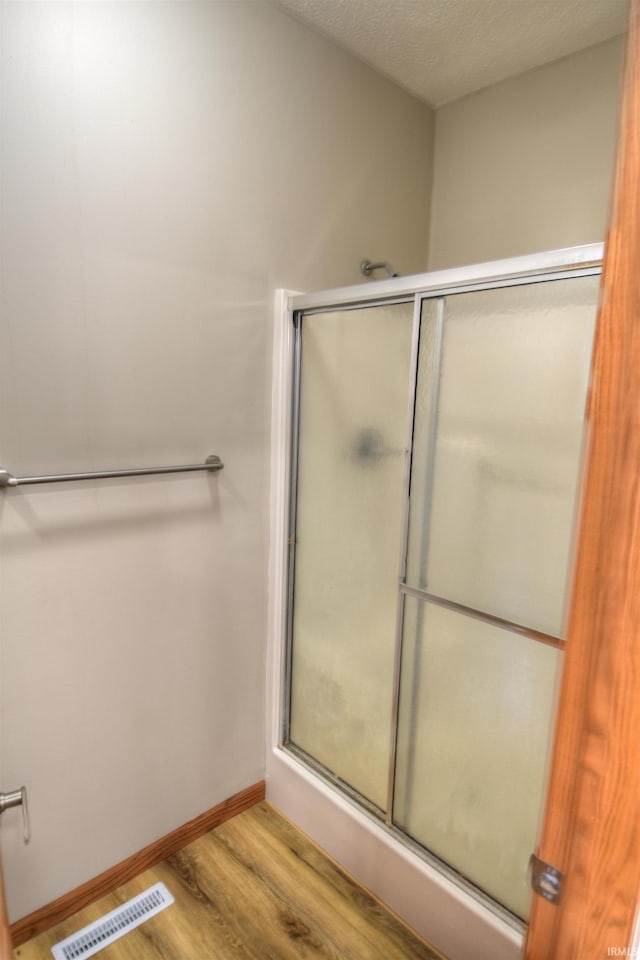 bathroom with hardwood / wood-style flooring, a textured ceiling, and walk in shower