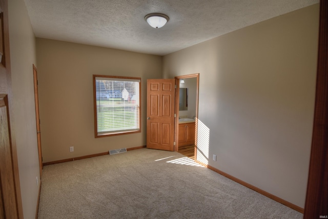 empty room featuring a textured ceiling and light carpet