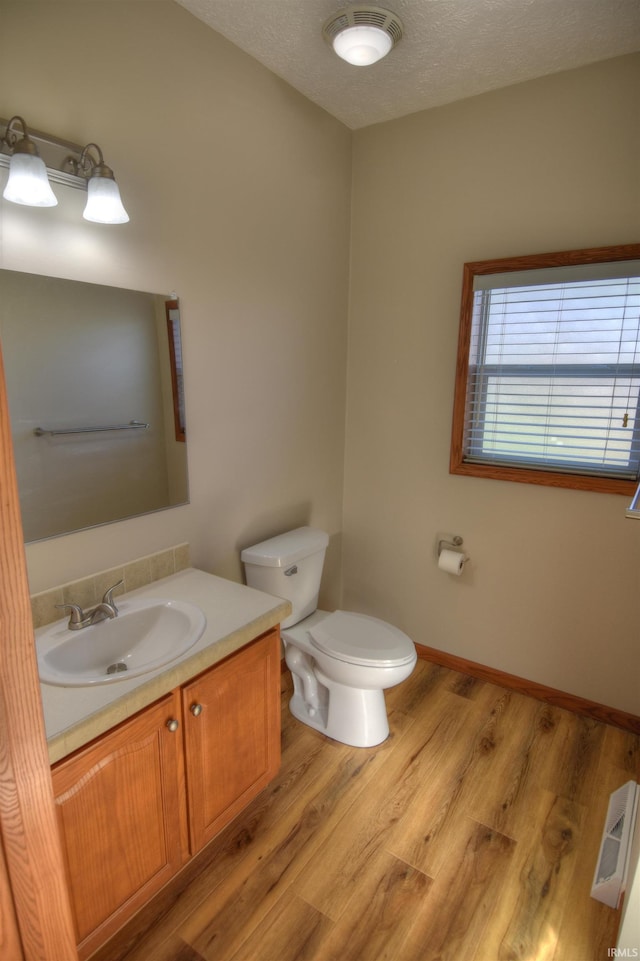 bathroom with toilet, vanity, a textured ceiling, and hardwood / wood-style flooring