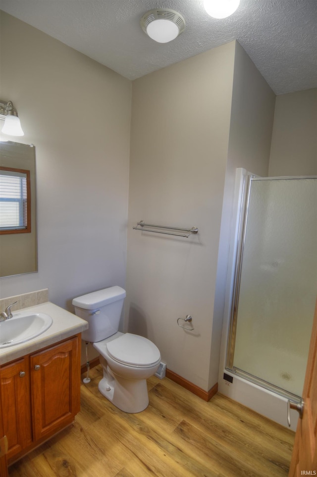 bathroom with vanity, a textured ceiling, an enclosed shower, hardwood / wood-style floors, and toilet