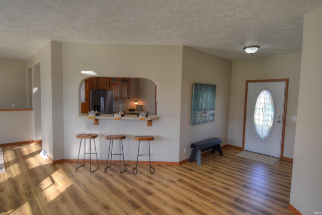 foyer entrance with light hardwood / wood-style flooring and a textured ceiling