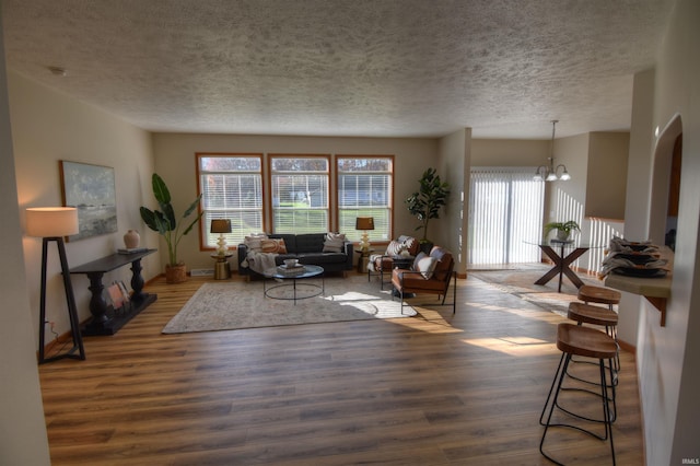 living room with a textured ceiling, dark hardwood / wood-style flooring, and a chandelier