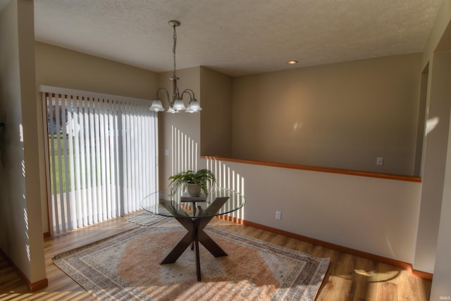 dining room with hardwood / wood-style flooring, a textured ceiling, and a notable chandelier