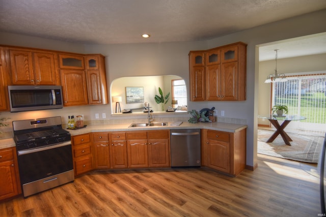 kitchen with hanging light fixtures, hardwood / wood-style flooring, sink, a chandelier, and appliances with stainless steel finishes