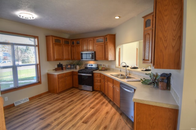 kitchen featuring a textured ceiling, light wood-type flooring, sink, and stainless steel appliances