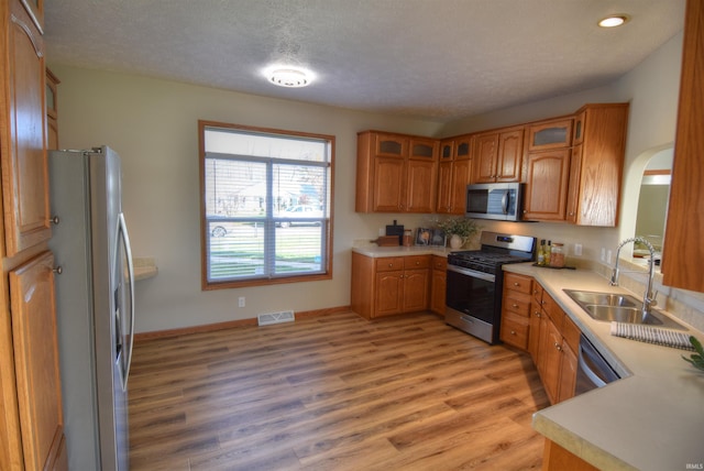 kitchen featuring stainless steel appliances, light hardwood / wood-style floors, a textured ceiling, and sink