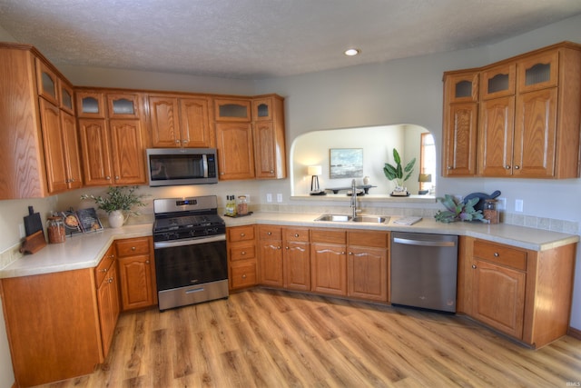 kitchen featuring a textured ceiling, stainless steel appliances, light hardwood / wood-style floors, and sink