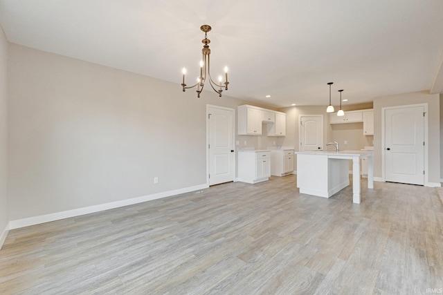 4805 Falcon Pkwy, New Haven, IN 46774 - kitchen with a chandelier, baseboards, light wood-type flooring, open floor plan, and white cabinets