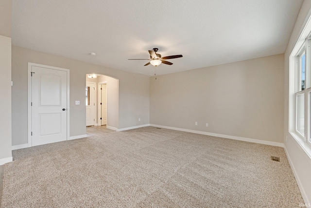 spare room with ceiling fan, light carpet, and a wealth of natural light