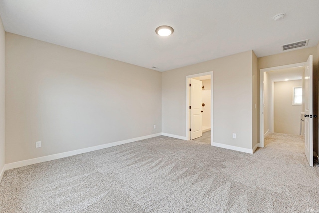 unfurnished bedroom featuring light carpet and ensuite bath