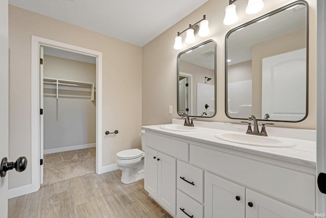 bathroom featuring a shower, hardwood / wood-style floors, vanity, and toilet