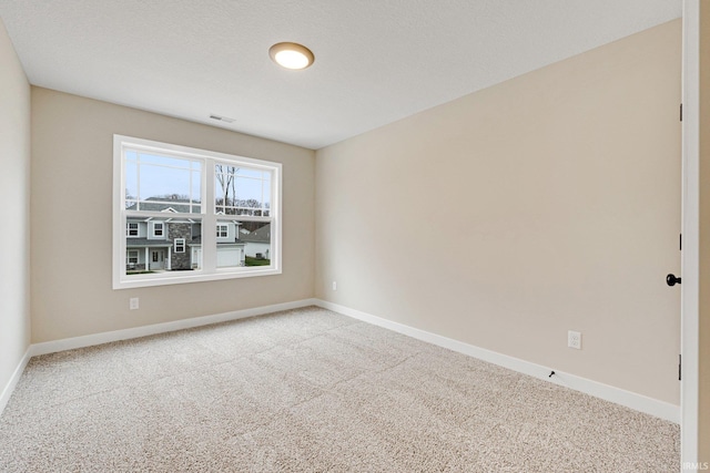 carpeted empty room featuring a textured ceiling