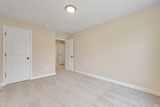 unfurnished room with light carpet and a textured ceiling