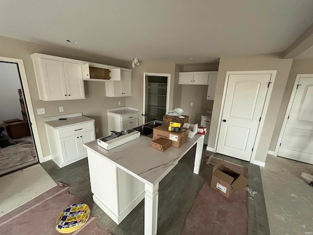 kitchen with a breakfast bar, a kitchen island, light stone countertops, and white cabinetry