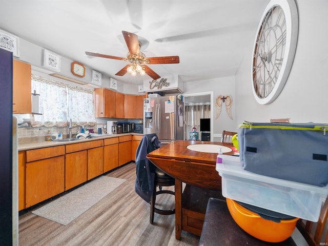 kitchen with stainless steel fridge, ceiling fan, decorative backsplash, light hardwood / wood-style flooring, and sink