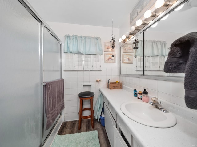 bathroom featuring hardwood / wood-style flooring, tile walls, a shower with shower door, and vanity