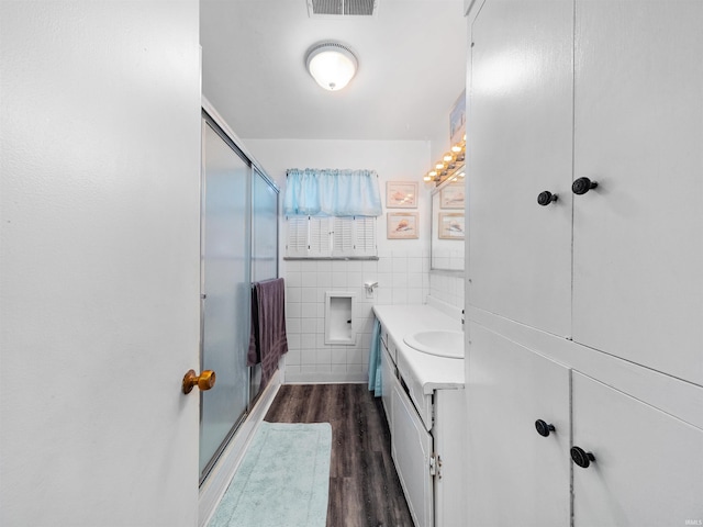 bathroom with hardwood / wood-style flooring, tile walls, an enclosed shower, and vanity