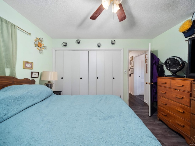 bedroom with ceiling fan, a textured ceiling, dark hardwood / wood-style floors, and a closet