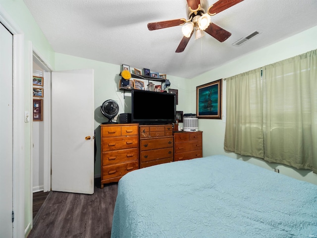 bedroom with ceiling fan, dark wood-type flooring, and a textured ceiling