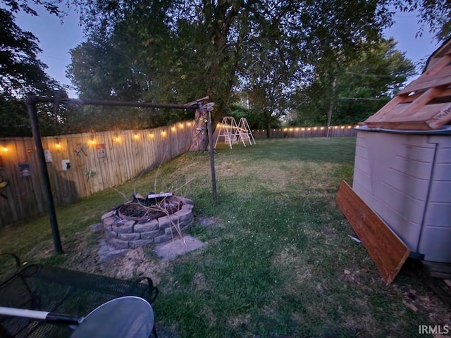 yard at dusk featuring a playground and an outdoor fire pit