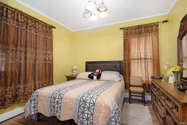 bedroom featuring a baseboard radiator, a notable chandelier, hardwood / wood-style flooring, a textured ceiling, and ornamental molding