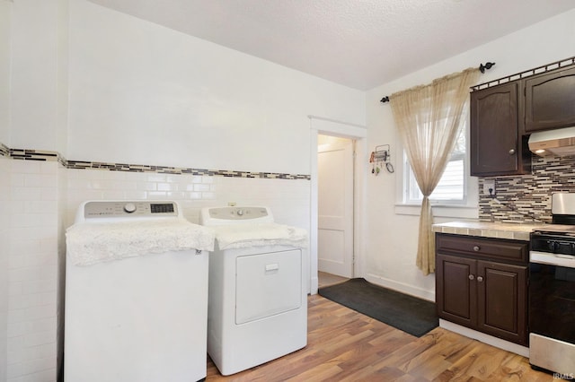 laundry area with light wood-type flooring, washing machine and dryer, and a textured ceiling