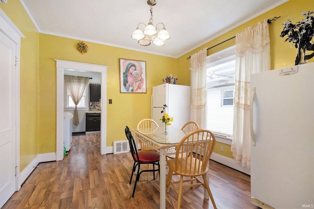 dining room with hardwood / wood-style floors, an inviting chandelier, and crown molding