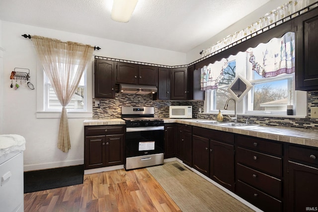 kitchen with dark brown cabinets, stainless steel range, light hardwood / wood-style floors, and tile countertops