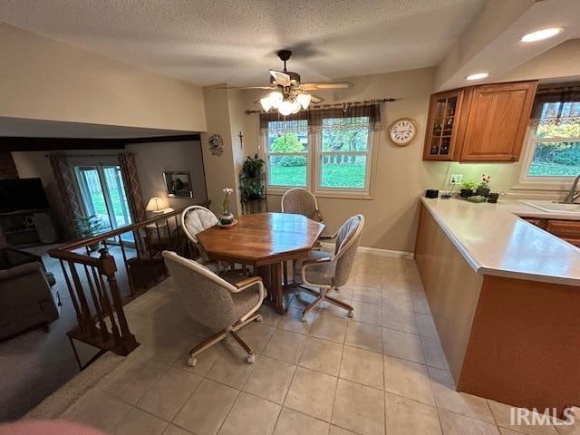 dining space with ceiling fan, a textured ceiling, light tile patterned floors, and sink