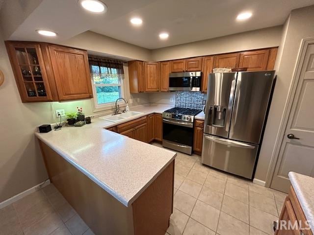 kitchen featuring stainless steel appliances, light tile patterned floors, sink, and kitchen peninsula