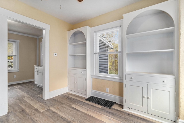 unfurnished dining area with light wood-type flooring, ceiling fan, and ornamental molding