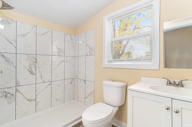 bathroom featuring vaulted ceiling, vanity, toilet, and a tile shower