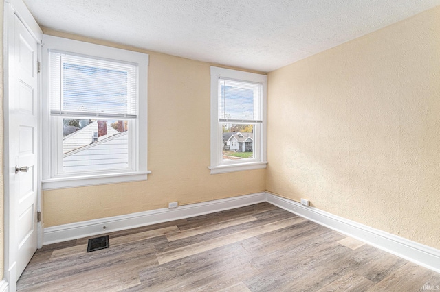 unfurnished room featuring a textured ceiling and hardwood / wood-style flooring