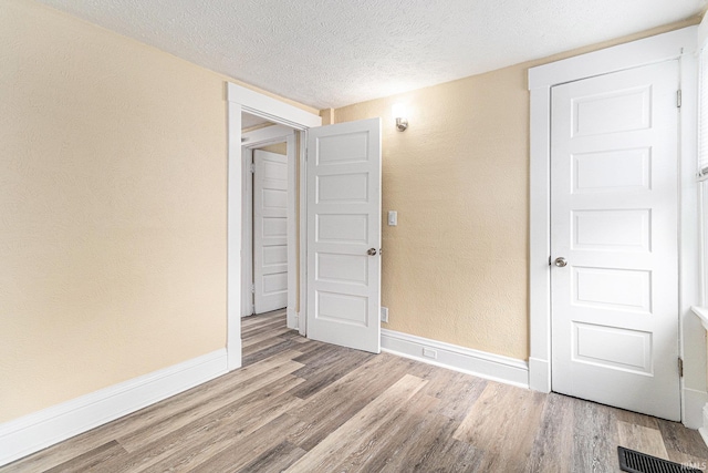 empty room with light hardwood / wood-style floors and a textured ceiling