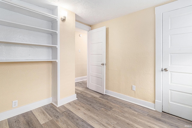 unfurnished bedroom with wood-type flooring, a textured ceiling, and a closet