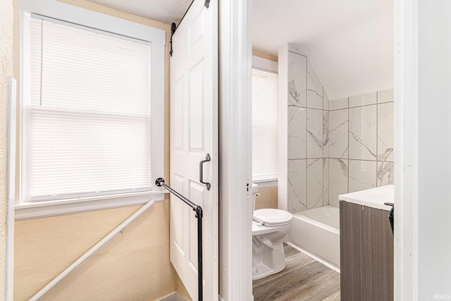 full bathroom featuring vanity, a textured ceiling, hardwood / wood-style floors, toilet, and tiled shower / bath