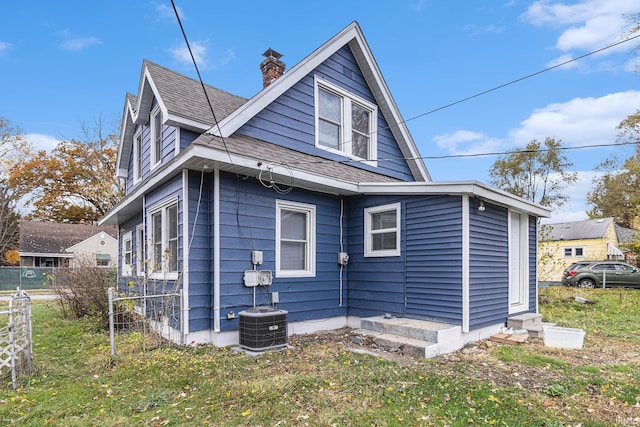 rear view of house with a lawn and central AC