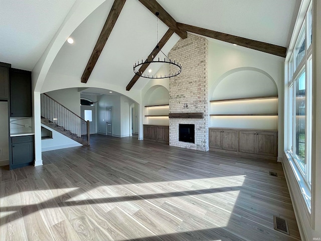 unfurnished living room featuring hardwood / wood-style floors, a fireplace, high vaulted ceiling, and beam ceiling