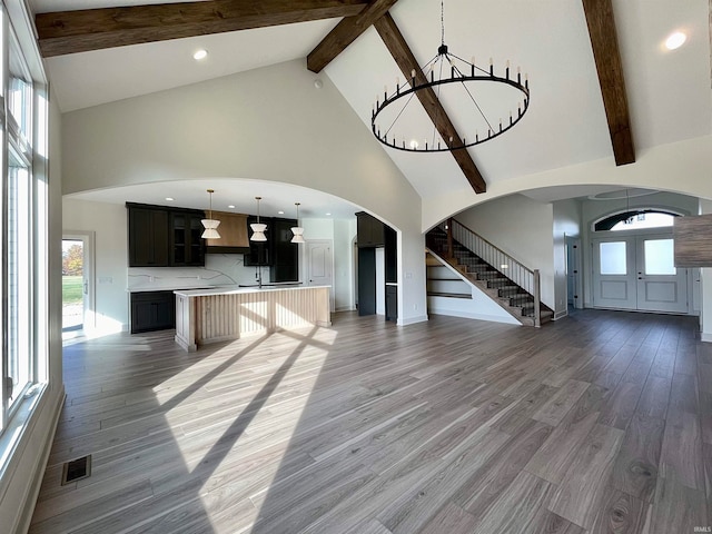 unfurnished living room with hardwood / wood-style flooring, plenty of natural light, and high vaulted ceiling