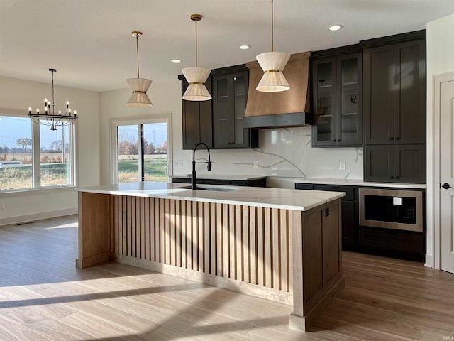 kitchen featuring light hardwood / wood-style floors, a center island with sink, sink, and stainless steel oven