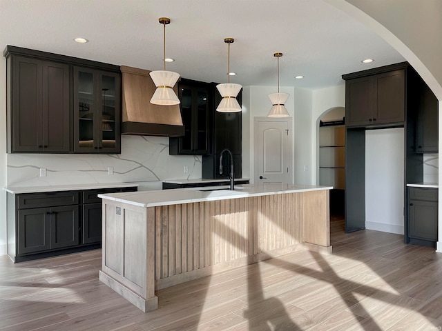 kitchen featuring light hardwood / wood-style floors, sink, a kitchen island with sink, and decorative light fixtures