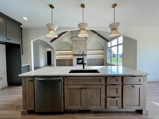 kitchen with lofted ceiling, light stone counters, hardwood / wood-style floors, stainless steel dishwasher, and pendant lighting